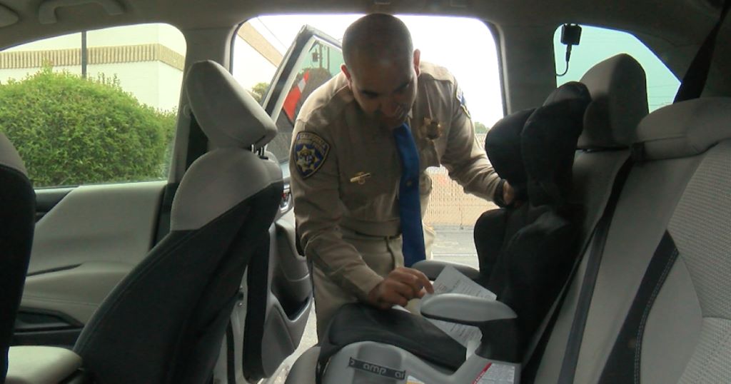 California Highway Patrol officer inspecting car seat.